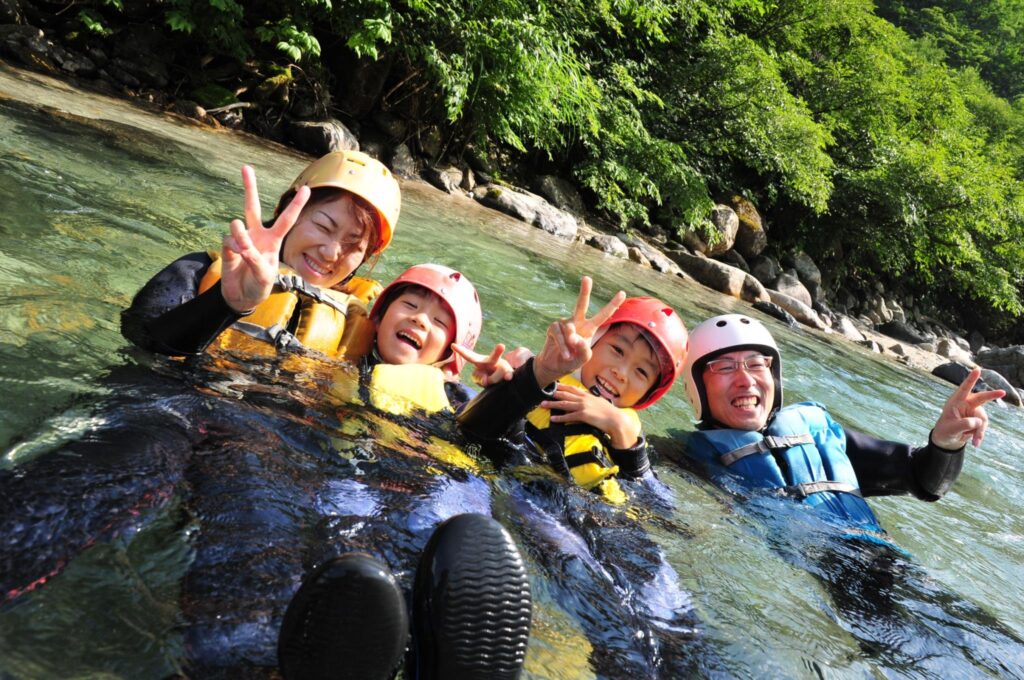 Foto de uma família japonesa se divertindo tirando férias em um parque aquático natural e nadando em um rio no Japão